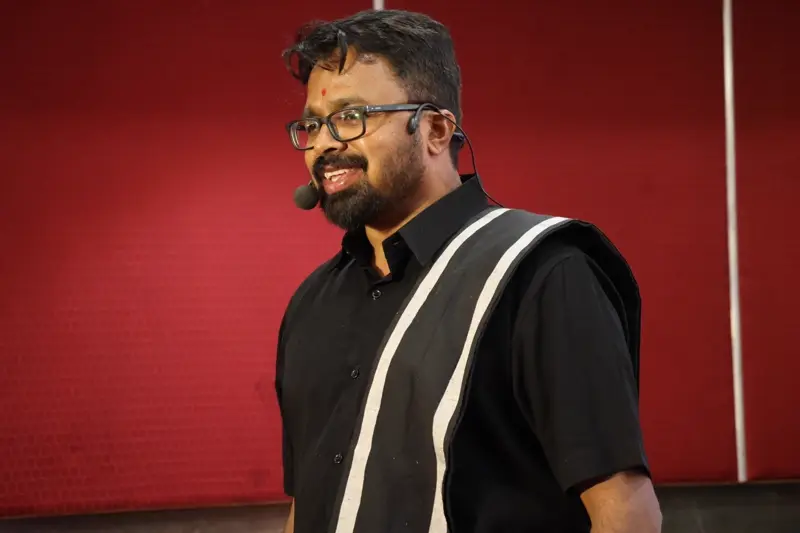 Guruji speaking on stage in a black outfit